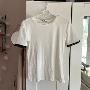 Vit topp med detaljer vid armen!  - Den är en ganska tight modell med fina detaljer vid armen. Den är använd en gång och tvättad en gång. (Porto tillkommer) 
