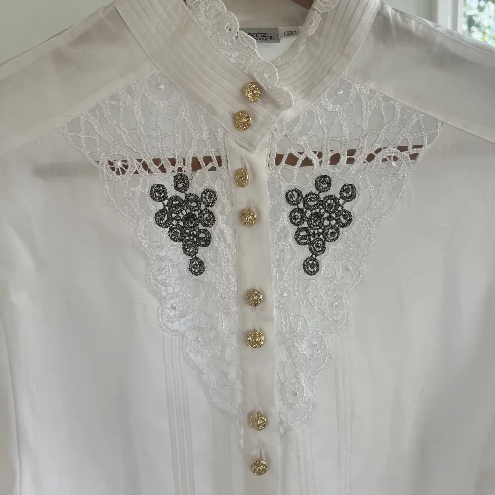 En vit lyxig skjorta med guld knappar och spets. Skjortan är från Grätz i stl 38 och har puff armar . Skjortor.