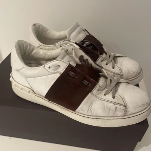 Valentino skor - Valentino rockstud med vinrött. Storlek 41,5. Ovanlig kombination då vinröda stripen är i kopäls. Köpta på Nathalie Schuterman i Sthlm. Orginal- låda och oanvända skosnören medföljer.  Dessvärre har lite av den färgade pälsen släppt (bild 3) 