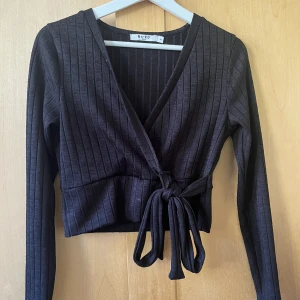 Omlott topp - Säljer min Svarta stretchiga omlott topp från NA-KD då den inte används längre.