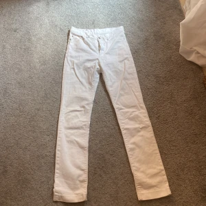 Vita lågmidjade jeans - Vita lågmidjade jeans som är raka/utsvängda. De har en detalj på baksidan och är i bra skick. Har knappt används.
