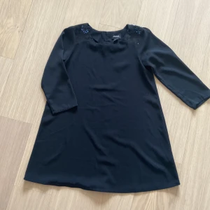 Klänning  - Svart elegant klänning från Monki. Knappar bak upptill. Paljetter på axlar. Den är superfin även med skärp. Ganska kort. Har fått många komplimanger med denna på!:)