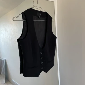Svart kostymväst  - En svart kostymväst från H&M med djup urringning. Lite för liten för mig. Jag står för frakten. Endast swish som betalningsmedel 🥰