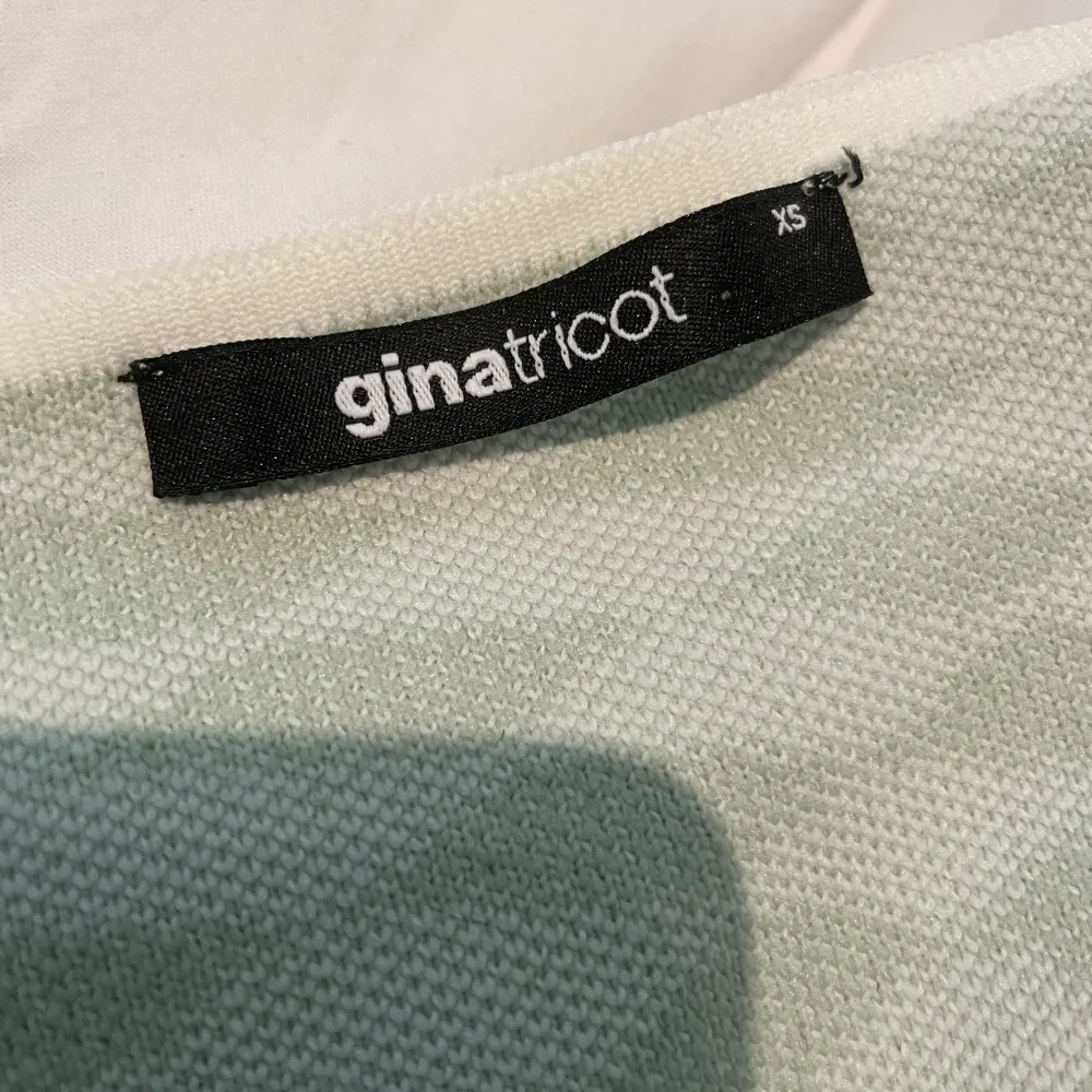 Vit/pastellgrön halterneck klänning  med asymmetriska rutor från Gina Tricot i superskönt material säljes💚 aldrig använd. Klänningar.