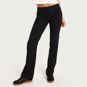 Lågmidjade kostymbyxor - Svarta lågmidjade kostymbyxor från Nelly i storlek 34. Har andvänt en gång! Nypris: 399