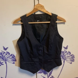 Svart väst - Snygg svart väst från Gina i storlek 40! Västen har 5 knappar i fram och går att spänna en del i bak. 