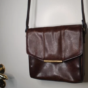 Axelväska - Väska i skinn , den har tre öppna fack plus två små fack inuti (ett öppet & ett m/ blixtlås) på utsidan finns ficka också. Kan skicka bild vid intresse.