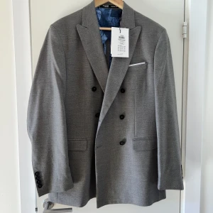 Grå blazer - Grå dubbelknäppt blazer från Selected Homme. Strl EU48. Nytt skick, aldrig använd  Nypris 1700:- 