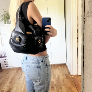 Marc Jacobs väska - En äldre modell från Marc Jacobs väska som köptes second hand. På bild 2 kan man se lite skador på själva ”skylten” där färgen släppt lite. Men annars inga skador. En mindre handväska som är perfekt till vardags. 