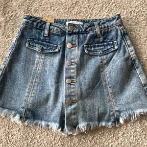 helt oanvända jeans short - ser ut som en kjol framifrån men shorts bakifrån, två slitsar längst ner och fake fickor där fram
