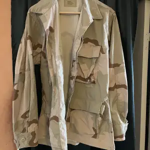 Säljer min Äkta (Nato märkt) Amerikanska Desert Camouflage jacka som är för liten för mig.  Storlek Medium short. 