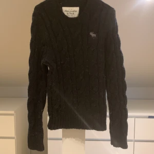 Stickad tröja - En mörkblå stickad tröja men loga på bröstet.