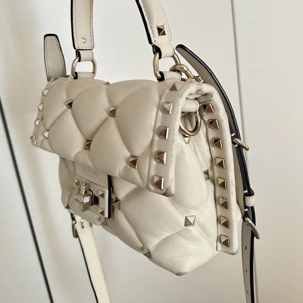   Så snygg Valentino väska i modellen candystud i en off-white färg som inte längre säljs. I den mindre storleken. Kommer med axelband och är i bra skick men lite slitningar på kanterna. Kommer med dustbag, kvitto och intyg. . Väskor.