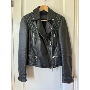 All Saints Cargo Biker Skinnjacka - En härlig All Saints-jacka av mjukt läder i fint skick. Lite nött vid ärmslutet men inget som påverkar intrycket.  Nypris ca 4000 kr.