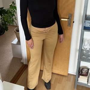 Festbyxor - Byxor i guldbeiged, lite 70-talsvibe. Köpt vintage för 500kr. Modellen på bilden är 164cm. Stretchiga material. Färgen är gul, beige guldig. Pris kan diskuteras
