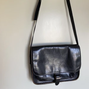 Äkta skinnväska svart, preppy 90-tal  - Äkta thriftad skinnväska. Får plats med cheomebook/ipad. Fungerar som vardagsväska. 90-tals stil. Några skavanker invändigt men gott skick utvändigt 