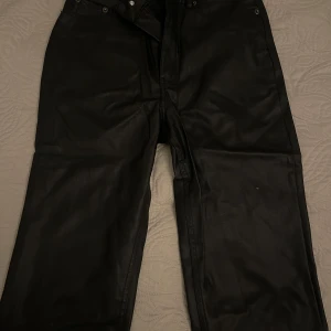 Utsvängda Läderbyxor  - Säljer dessa snygga läderbyxor från Asos likt modellen ovan. Utsvängda med medel-hög midja. Endast använd 1 gång så inga defekter. Superskönt material med stretch. Stl 34 men passar 34-36. 