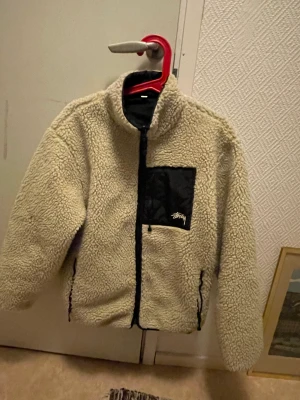 Stussy 8ball fleece reversible  - En Stussy 8ball fleece köpt av en kompis, osäker på hur äkta den är, säljer den då den inte är min stil längre. Den går att vända ut och in kom privat för mått eller fler bilder