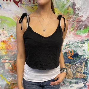 Svart croppat linne med snörning  - I fint tjockt linnematerial, snyggt att styla med vitt linne under. Storlek S/M. Modellen är 175 cm. Hör av er vid frågor/fler bilder. 