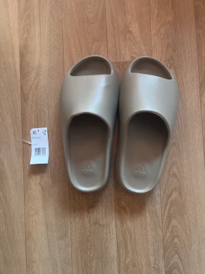 Yeezy slides coffee - Coffee yeezy slides  Ny skick men har ett par rynkor typ (se bild 3) från när de transporterats. (Där av priset) Köpte av sc.hypee för typ 2 månader sen. Skaffat nya (svarta) där av säljer ja de nu.  knappt andvända Condition 7.5/10