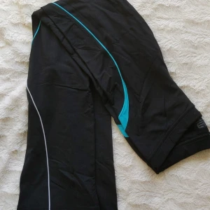 Svarta bootcut träningsbyxor - Svarta träningsbyxor. Lite halvhög midja. Utsvänga vid benen. Blå ränder på.