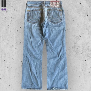 True religion jeans #703 - True Religion jeans i model Bobby Super T 💜 Tag 32W 💜Midja (rakt över) 42cm 💜 Innerben 76cm 💜 Ytterben 100cm 💜 Benöppning 21cm 💜 nedgågna, små fläckar och lagade p framsidan 💜Våra mått blir W=33, L=29 💜 Men jämför alltid måtten💜703