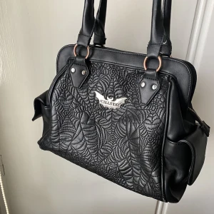 KILLSTAR väska - Väska från Killstar *Webutant Handbag* lite slitningar på på själva axelbanden men inget som är trasigt. Inga slitningar på själva mönstret heller. Väskan har 3 stycken stora fack (se sista bild) man kan stänga mittenfacket med dragkjedja. Stor och rymlig