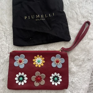 Skinn väska/ clutch  - Supersöt clutch / necessär i äkta skinn från det Italienska märket Piumelli.  Aldrig använd med dustbag då det var en present som inte föll mig i smaken, men blir nog perfekt som present till nåns svärmor, moster? 🥰19x 11 cm