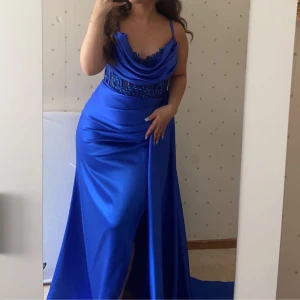 Festklänning - En vacker festklänning i satin med en fantastisk modell upptill, slit vid sidan, med släp ovan. Använd ett par timmar. Storlek 38/40. Nyskick