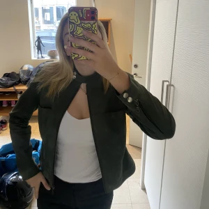 Grön mocka-jacka  - As snygg mörkgrön mocka-jacka som har knäppe vid halsen. Storleken är 12= M men skulle säga att den är liten o passar nog bäst på s-xs 