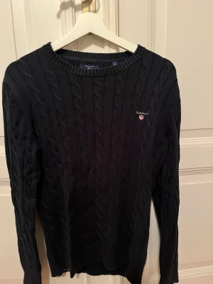 Mörkblå stickad tröja från Gant - Mörkblå kabelstickad tröja från Gant. I bra skick och i storlek M, men är som S/M. 