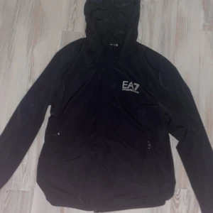Ea7 vindjacka äkta - En vindjacka/regnjacka i väldigt bra skick knappast använd.  Storlek S  Funkar perfekt under vind och regn.  Använd ett fåtal gånger. Ny pris 1500kr Äkta så klart.