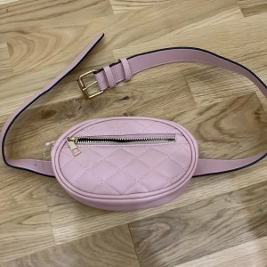 Magväska  - En rosa magväska som har som ett bälte 