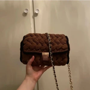 Väska - Brun väska med svarta kanter och sidor. Väskan är smyckad med guldfärgade detaljer - guldkedja med svart fakeskin och ett guldfärgat lås.  längd: 24.5 cm höjd: 17 cm bredd: 6.5 cm. OBS!! Katt finns i hushållet