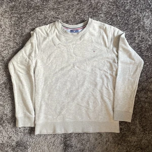 Grå ”Gant” Crewneck - Grå Gant Crewneck. Storlek 170 (15yr). Knappt använd, inga märken/hål/smuts och kvaliten är väldigt bra. Kunden betalar frakten 😚.