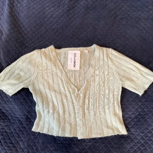 Stickad kofta strl 34 - En söt croppad stickad kofta i ljusgrå färg från Collusion ❄️ Stängs med knappar. (Frakt ingår ej)