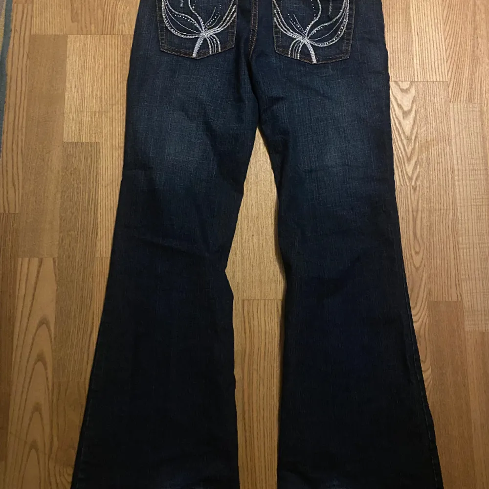 jätte snygga lågmidjade jeans med print på fickorna och lite slitningar. köpt secondhand men med lite användning. långa på mig, är 158. pris går att diskutera!. Jeans & Byxor.