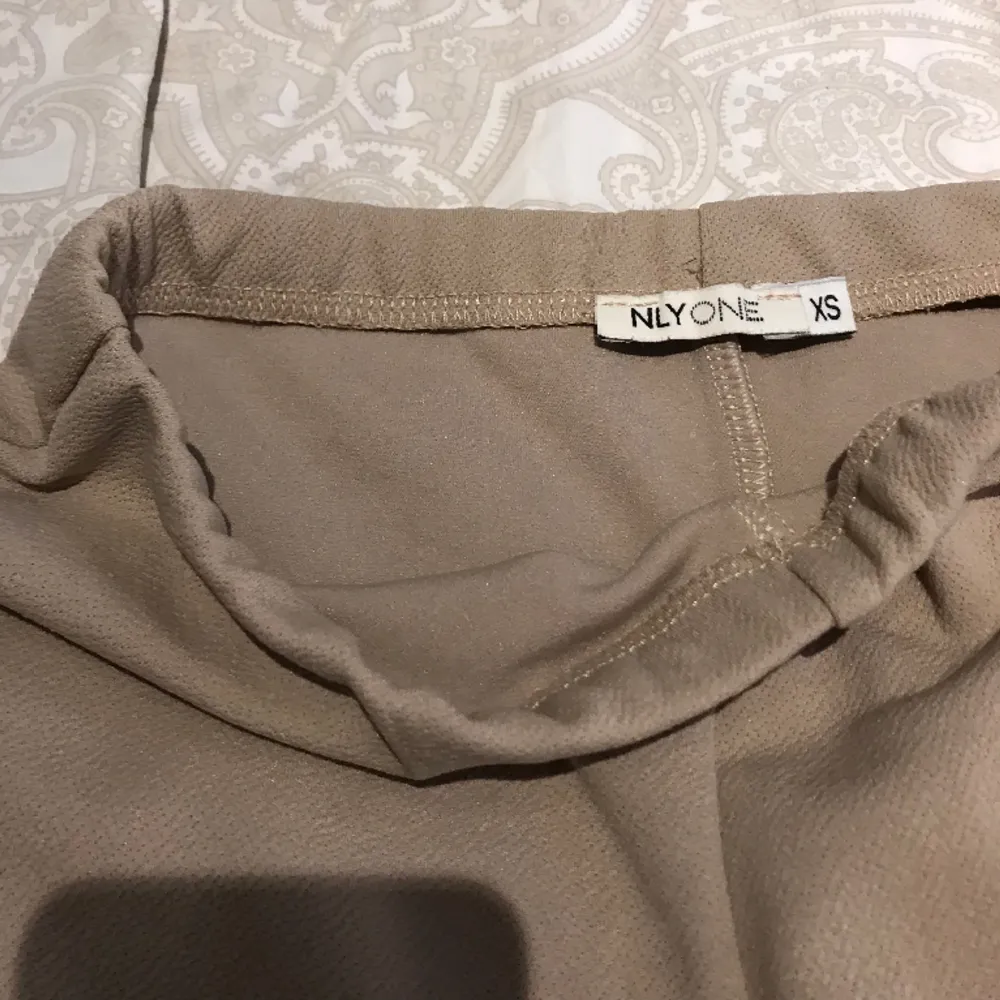 Beige/bruna byxor från Nelly i storlek xs. Använt fåtal gånger. Midje mått rakt över 34 cm, innerbenslängd  84. Jeans & Byxor.