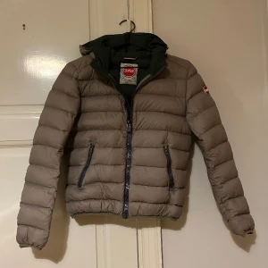 Colmarjacka  - Jättefin dunjacka med luva från Colmar i khakigrön, med mörkgrön insida. Det enda som har blivit lite slitet är ”släden” på dragkedjan (se bild). Annars är jackan i fint skick! Jackan är egentligen i storlek 42, men är liten i storleken, mer som 36/Small!