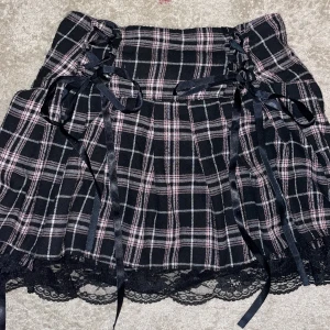 E-girl kjol💕 - En kort, rosa och svart mönstrig kjol med svarta rosetter på. Kontakta mig om mer info💕