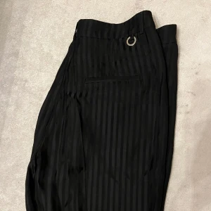 Kostymbyxor med slits, STOCKH LM - Svarta raka kostymbyxor med slits. Tyget är följsamt och något glansigt med subtila ränder. Använda fåtal gånger då jag köpte fel storlek!🥰