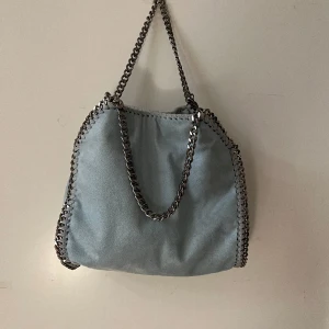 Stella McCartney Väska - Ljusblå Stella väska. Vattenskadad, fläckig därför sänkt pris. Fläckarna syns inte så tydligt när man är i vanligt ljus.