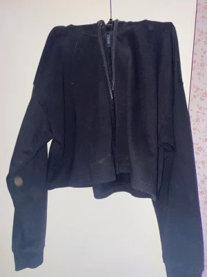 Svart zip-uptröja - Denna är aldrig använd och den är i bra skick! Den är kort vid midjan