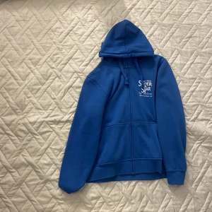 Blå zip hoodie - En bli zip hoodie med text på. Storlek L/42. Inga synliga skador. Kontakta mig privat för fler frågor eller om ni vill ha fler bilder✌️😊