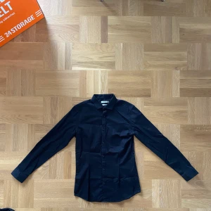 Svart skjorta Jack & Jones - Svart skjorta från Jack & Jones i storlek Medium för herr. Har ej strukit, därav väck här och var. Den är stretch i modellen vilket bidrar till en skön passform. Annars är den i gott skick! 