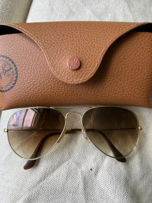 Rayban aviator guld bruna  - Nypris 1799:-   Ray-Ban AVIATOR 001/51 brun/guld  Mer info: https://www.synoptik.se/solglasogon/805289305026_AVIATOR/805289305026?gclid=EAIaIQobChMImrqhh6L8_gIVisuyCh2eMQUREAQYAyABEgKCRvD_BwE&gclsrc=aw.ds  Bruntonade glas. Förbättrat djupseende och kontra