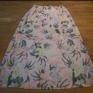 Blommig kjol - En blommig rosa kjol från Hm Den har en kort inbyggd kjol innanför den långa. Storlek L men passar M och är stretchiga i midjan så passar nog XL med