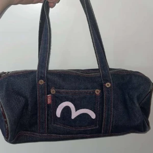 Evisu handväska  - En fin äkta Evisu handväska! I nyskick helt oanvänd utan några defekter. Jättefin att använda till vardagen. Nypris 2600kr men säljs för 500kr då jag inte har någon användning för den😅