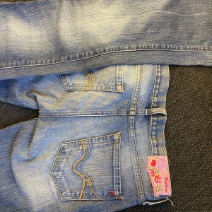 Blå jeans från Replay - Blå jeans med rosa detaljer! Bra kvalite, varsamt använda säljer för de är för små för mig 