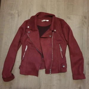 Jacka - Vinröd lite kortare jacka i mockaliknande material. Aldrig använd. Nypris 799 kr.